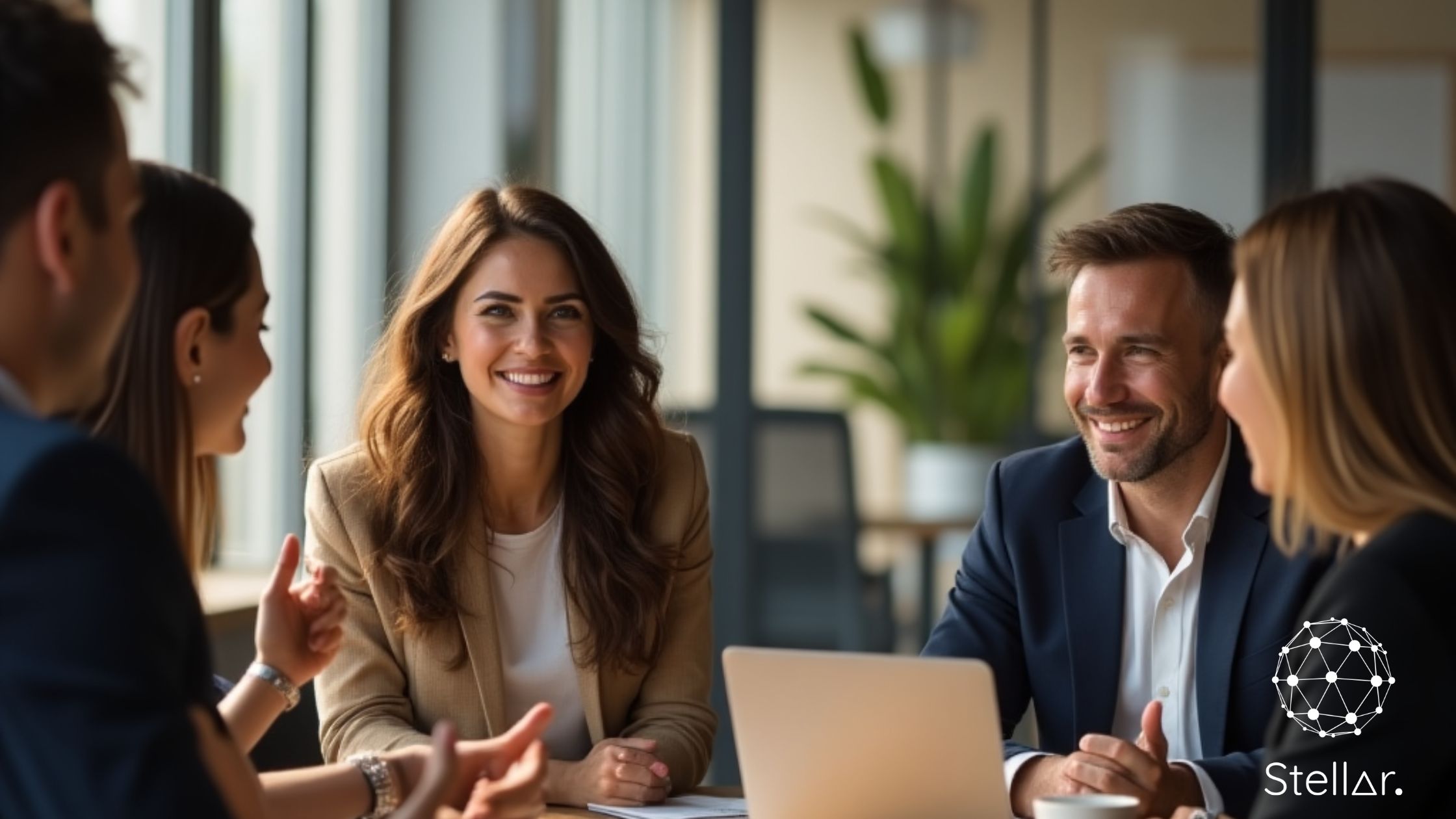 Four professionals in conversation around a laptop — a candid mentoring moment between mentors and mentees